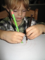 student drawing a circle with a piece of string that wraps around the central tether. As the string gets shorter the points get closer to the centre.
